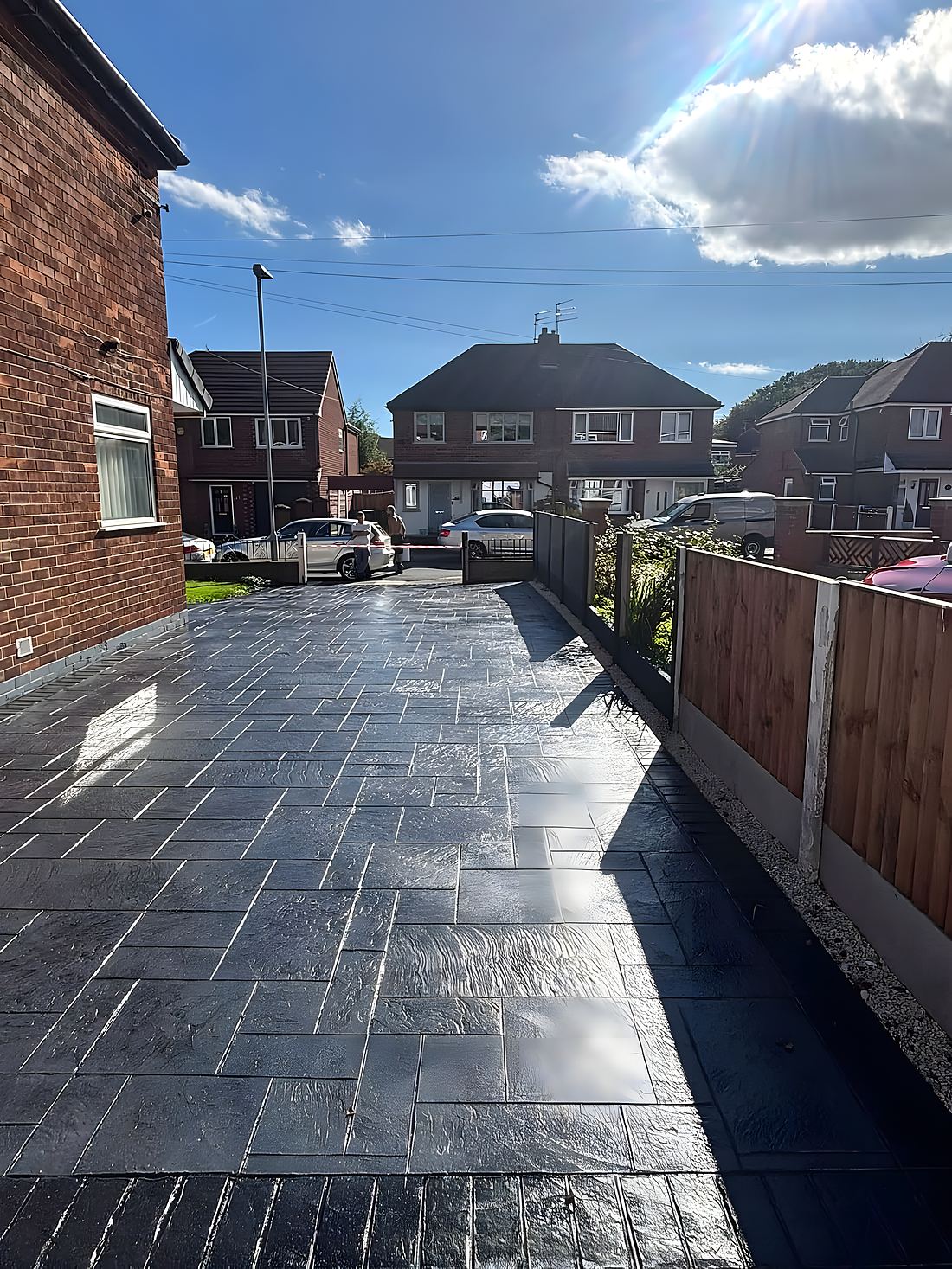A pattern-imprinted concrete driveway with a slate-grey finish